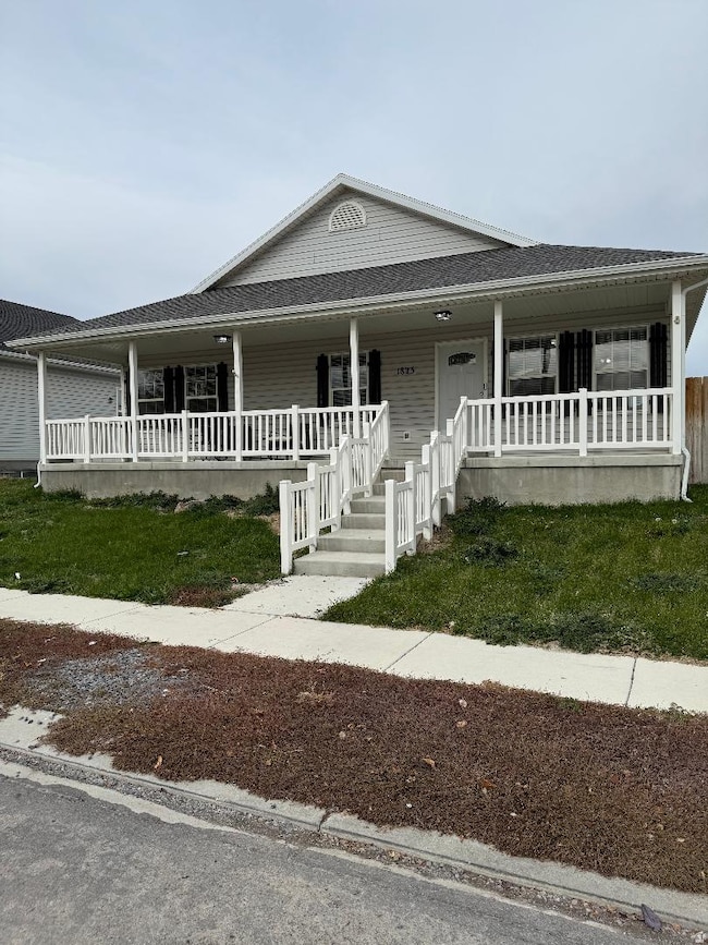View of front of house featuring covered porch, a shingled roof, and a front lawn