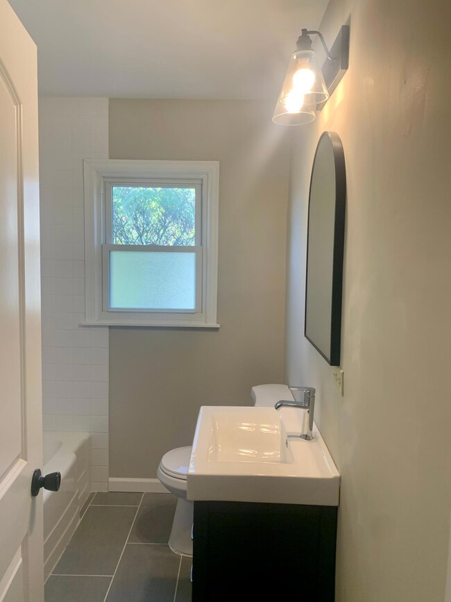 Full bathroom on main level with a functional three drawer vanity and beautiful arched mirror.