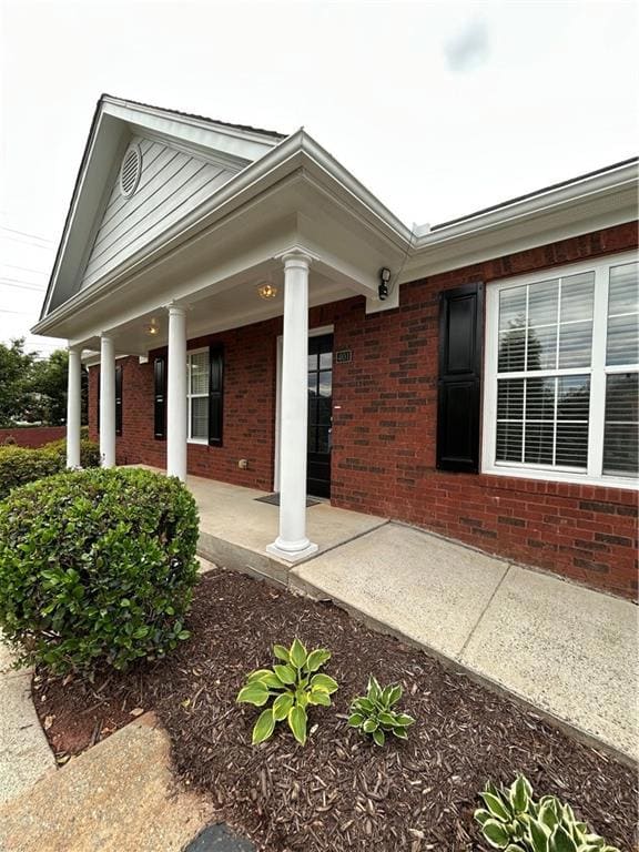 Property entrance featuring brick siding and a por