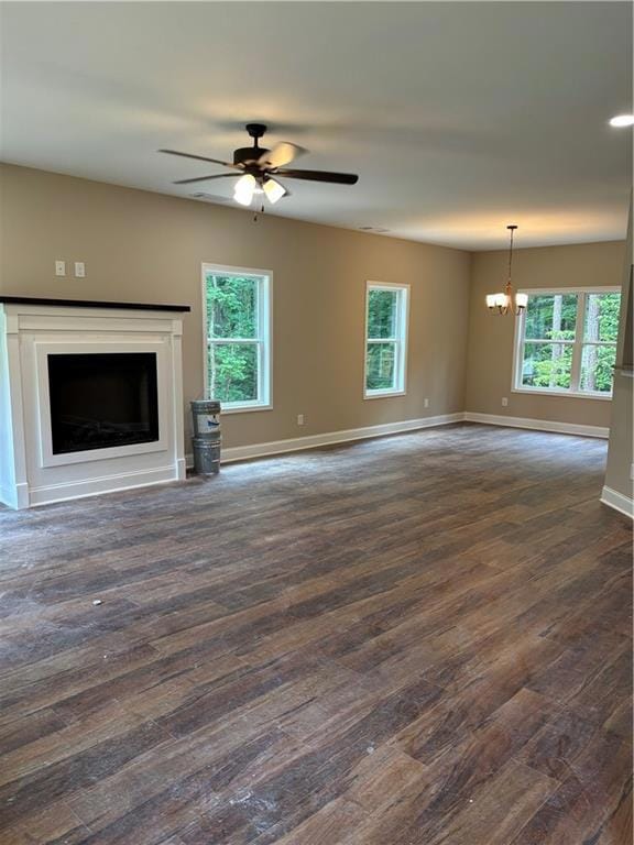 Unfurnished living room with dark wood finished floors, a chandelier, a fireplace, and ceiling fan