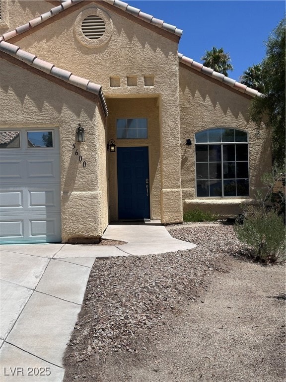 Doorway to property featuring stucco siding, a til