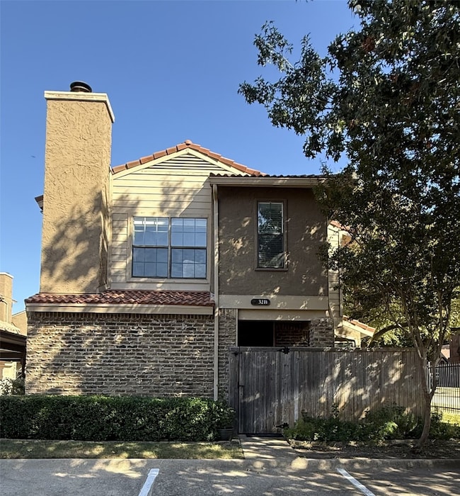 View of home's exterior with a fenced front yard, stucco siding, uncovered parking, and a tiled roof