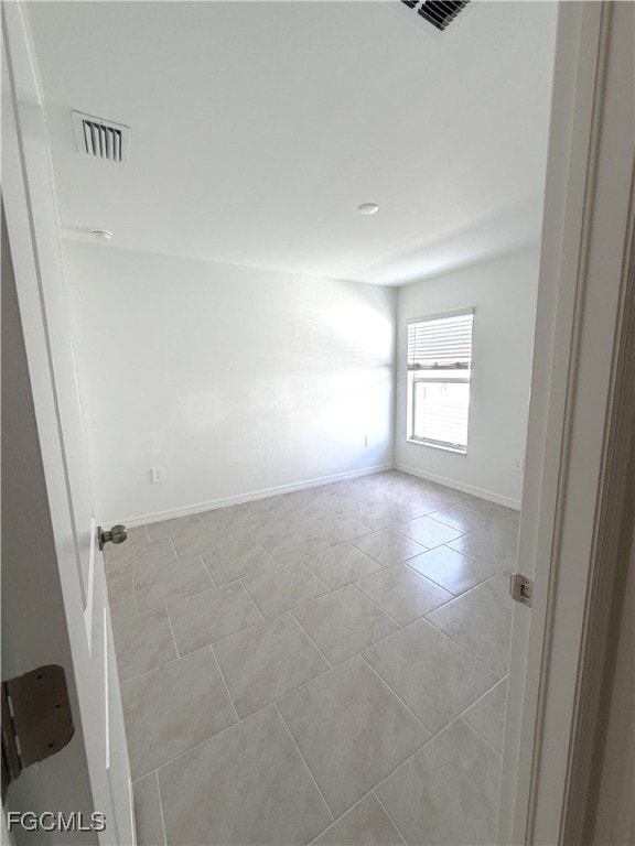 Spare room featuring baseboards and light tile patterned floors