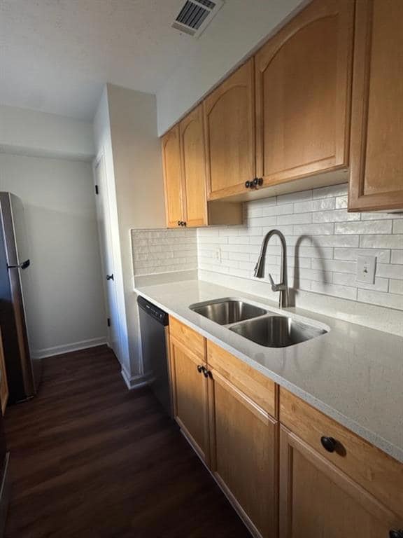 Kitchen featuring dark wood-type flooring, freestanding refrigerator, decorative backsplash, and dishwasher