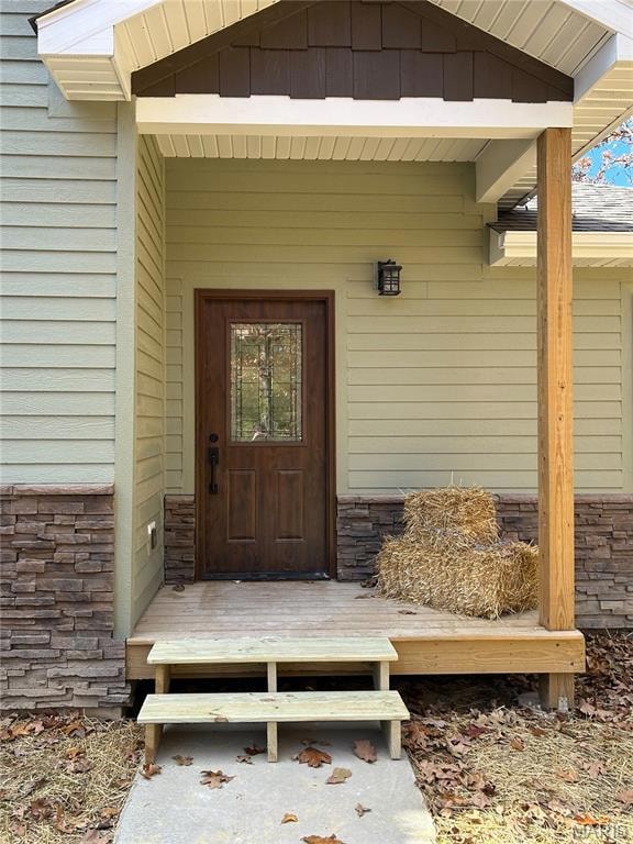 View of exterior entry with stone siding and a deck