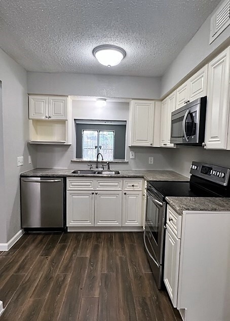 Kitchen boast off white cabinets, granite, and sta
