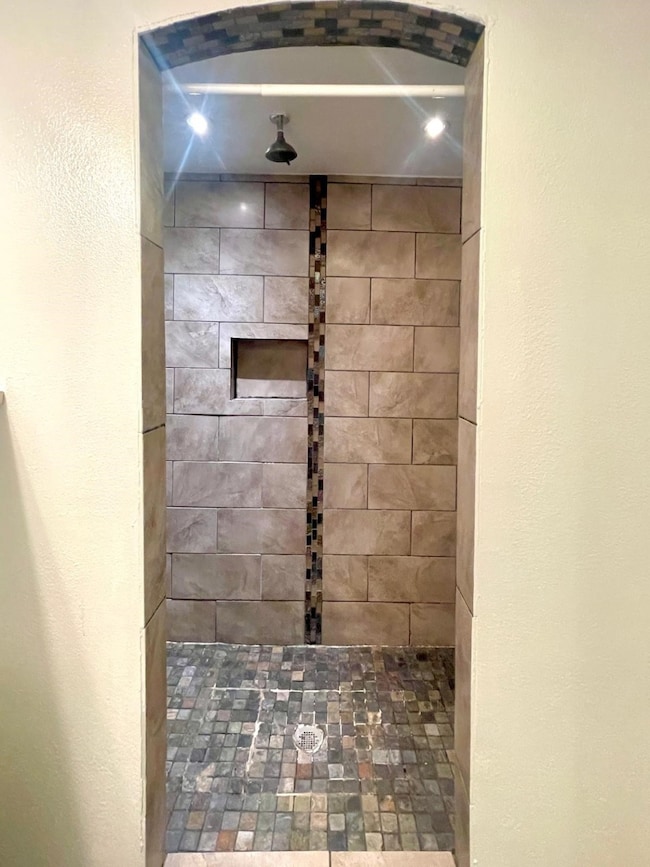 Bathroom with a textured wall and tiled shower
