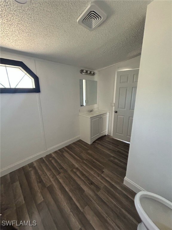 Bathroom with vanity, a textured ceiling, baseboar