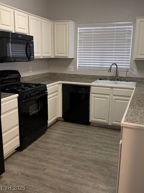 Kitchen with black appliances, white cabinetry, and dark wood finished floors