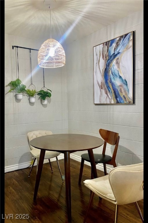 Dining area featuring concrete block wall and wood finished floors