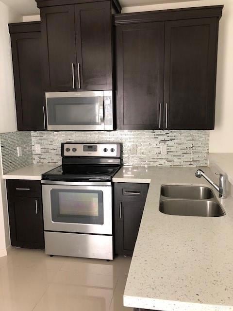 Kitchen featuring stove, light countertops, tasteful backsplash, and a sink