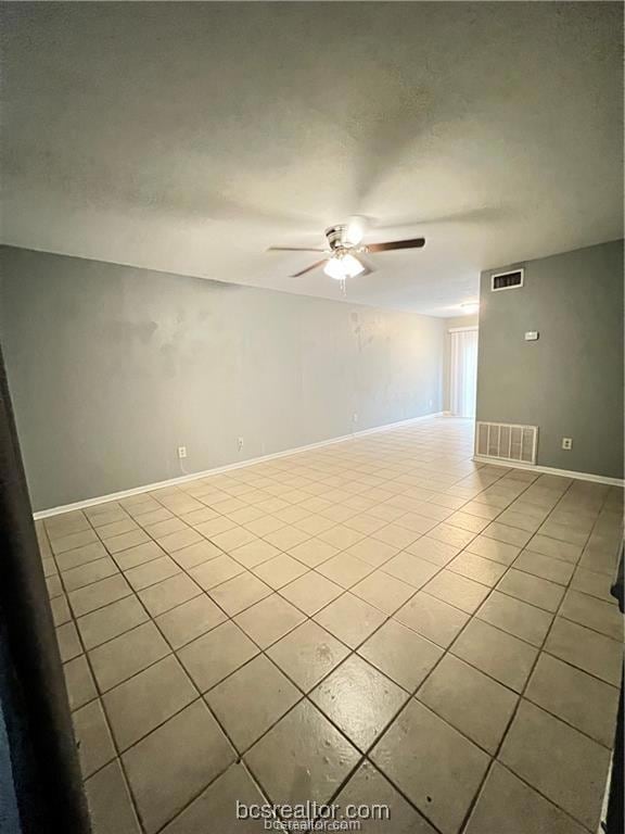 Empty room featuring ceiling fan and light tile pa