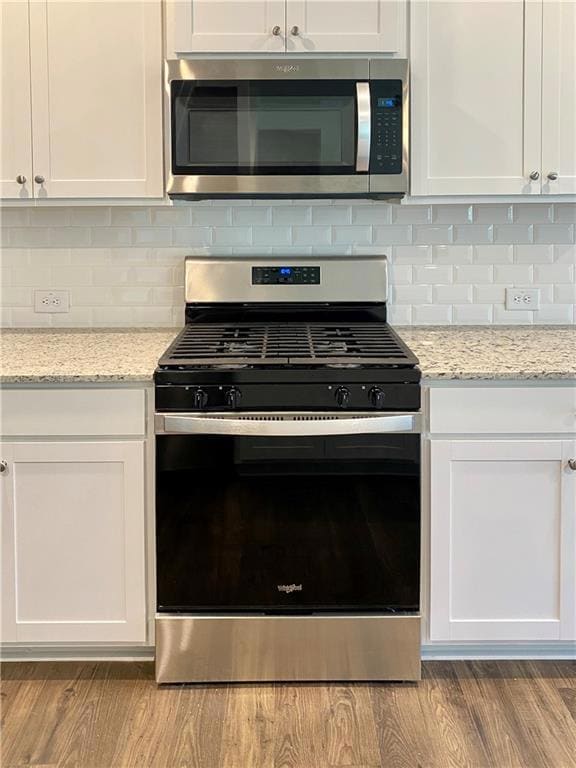 Kitchen with stainless steel refrigerator with ice dispenser, ornamental molding, white cabinetry, dark wood-type flooring, and backsplash