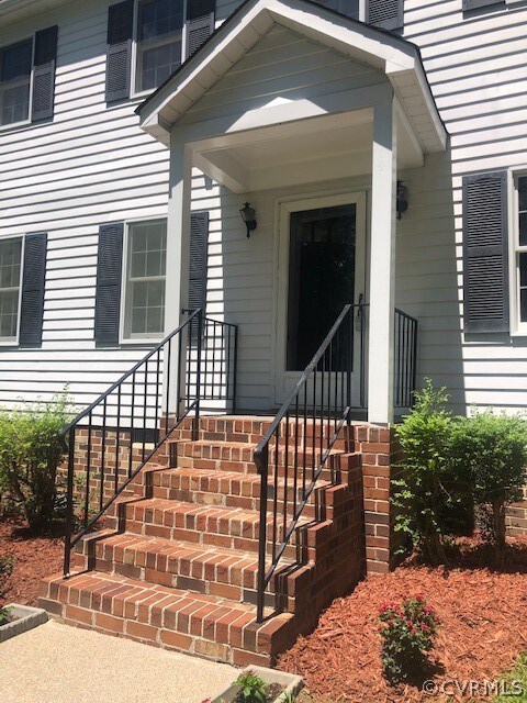The covered entryway with metal railing and brick
