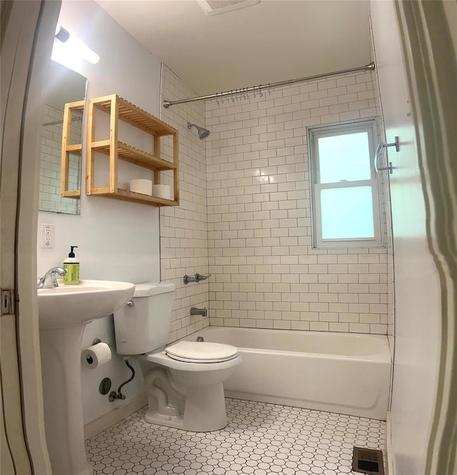 Bathroom featuring bathing tub / shower combination and light tile patterned flooring