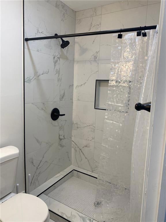 Bathroom featuring toilet and a stall shower