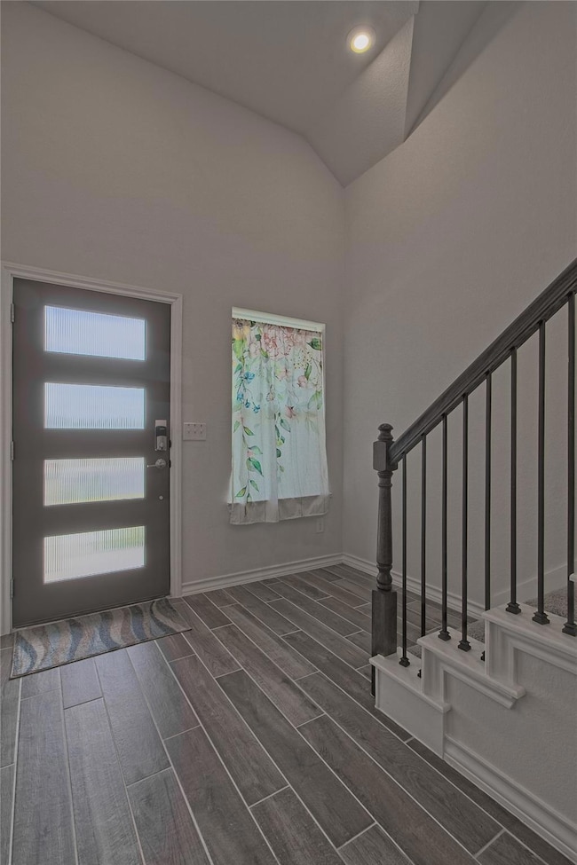 Foyer with stairs, wood tiled floors, and vaulted