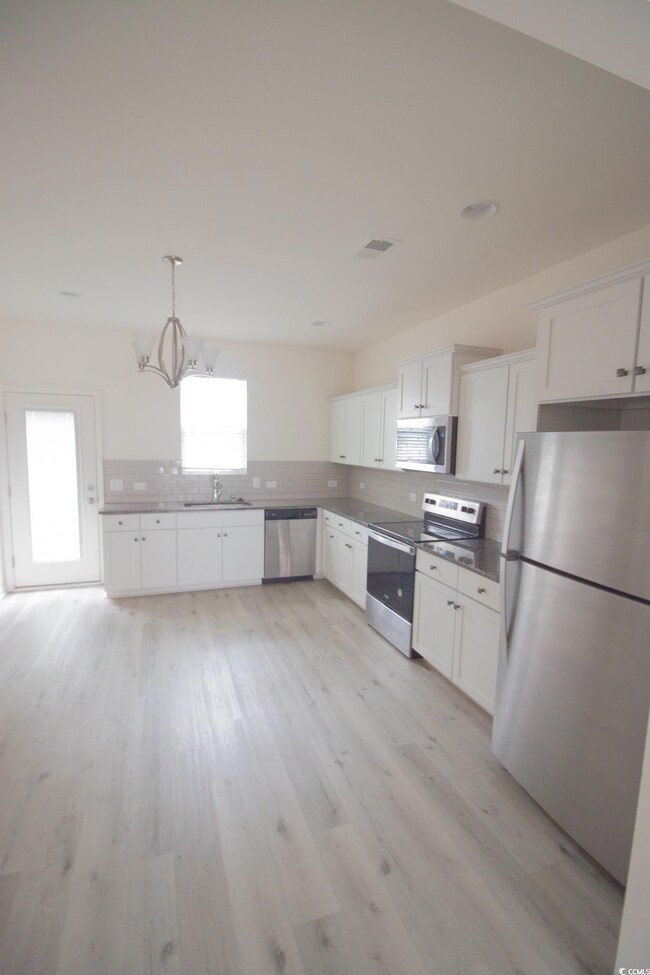 Kitchen with stainless steel appliances, a sink, tasteful backsplash, and white cabinetry