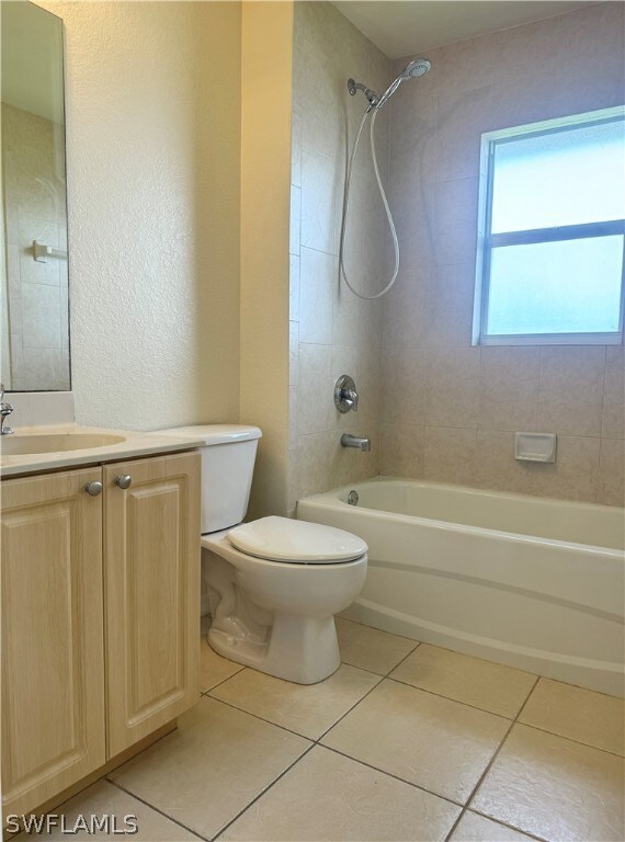 Full bathroom featuring tiled shower / bath combo, vanity, tile patterned floors, and toilet