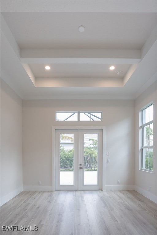 Spare room featuring light wood finished floors, a tray ceiling, recessed lighting, and french doors