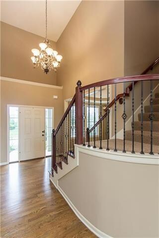 Two story foyer has curved staircase with metal sp
