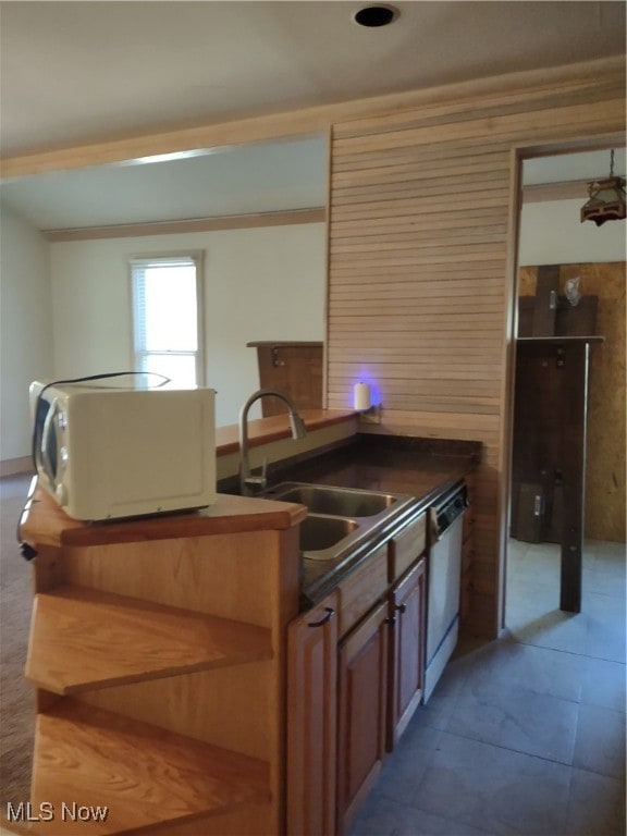 Kitchen with dark countertops, brown cabinets, dishwasher, ornamental molding, and wood walls