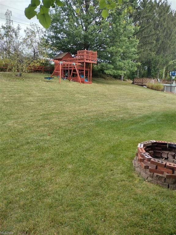 View of yard featuring a playground and a fire pit