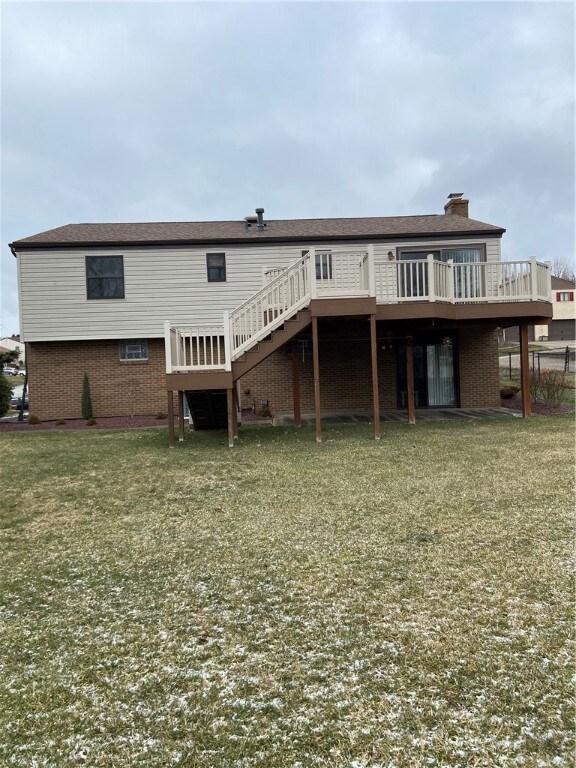 Back of home with large deck and flat yard