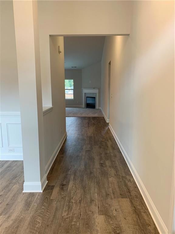 Hallway with dark wood-type flooring and baseboard