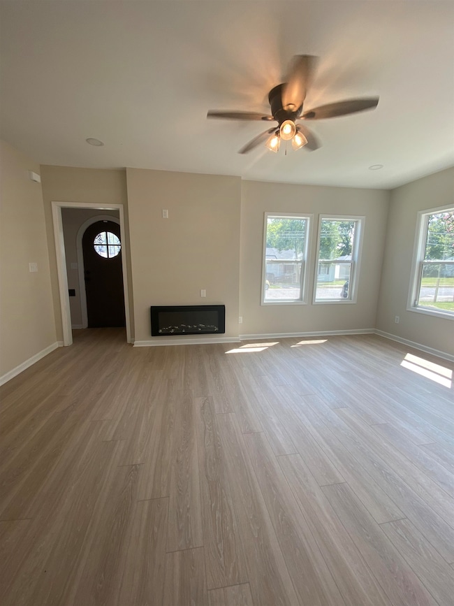 Unfurnished living room featuring light wood-style floors and ceiling fan