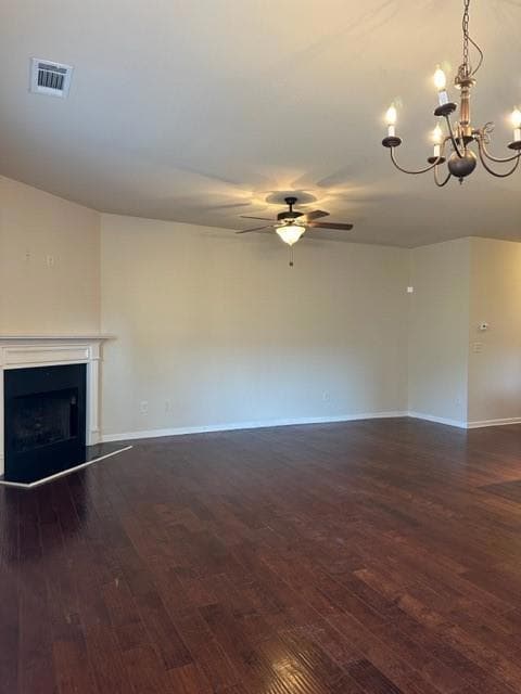 Unfurnished living room featuring ceiling fan, dark wood-style flooring, a fireplace, and a chandelier