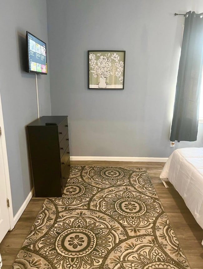 Bedroom featuring dark wood finished floors and baseboards
