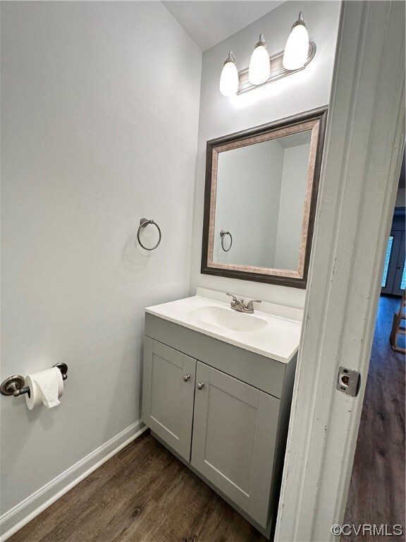 Bathroom with dark hardwood flooring, vanity with extensive cabinet space, and mirror