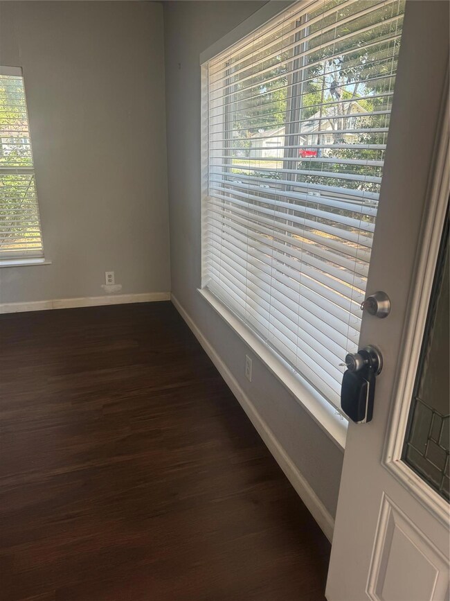 Empty room with dark wood-type flooring and a healthy amount of sunlight