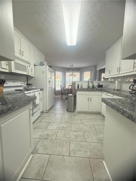 Kitchen featuring stove, a peninsula, a textured ceiling, dark countertops, and a sink