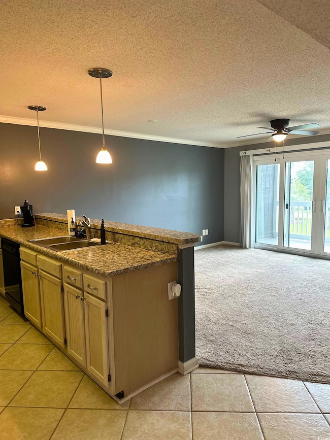 Kitchen featuring dark countertops, ornamental molding, a textured ceiling, decorative light fixtures, and light tile patterned flooring