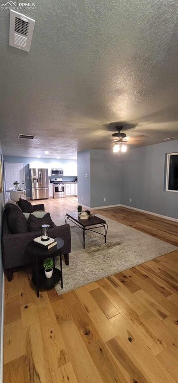 Living room featuring ceiling fan, a textured ceil