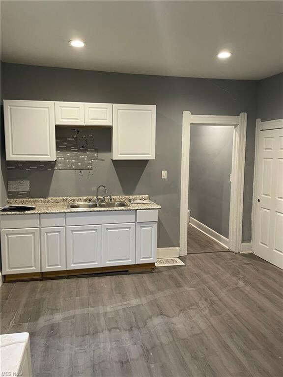 Kitchen with wood-type flooring and white cabinetry
