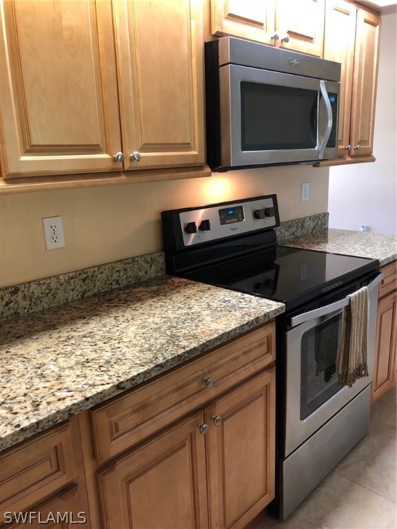 Open concept kitchen with stainless steel appliances, granite and wood cabinets.