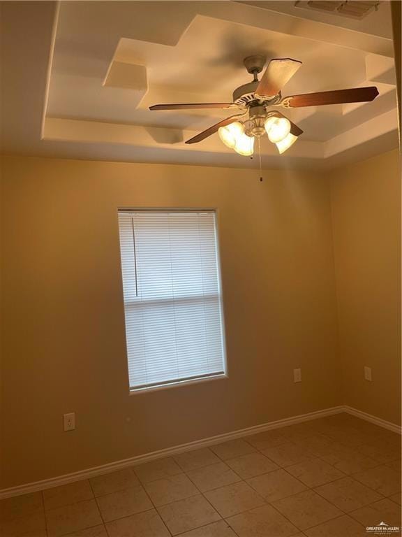 Unfurnished room featuring a tray ceiling, light tile patterned flooring, baseboards, and ceiling fan