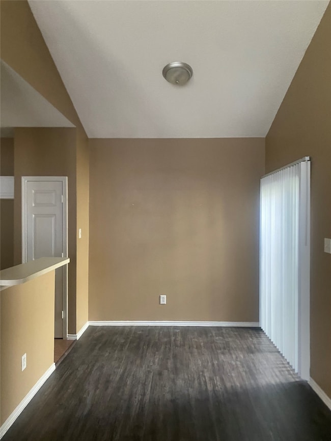 Spare room with vaulted ceiling and dark wood finished floors