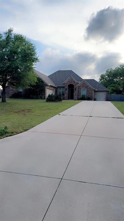 View of front facade featuring concrete driveway, an attached garage, a front yard, and brick siding