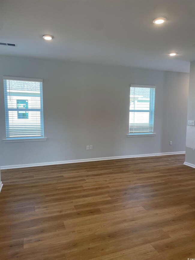Unfurnished room with dark wood-style floors, rece