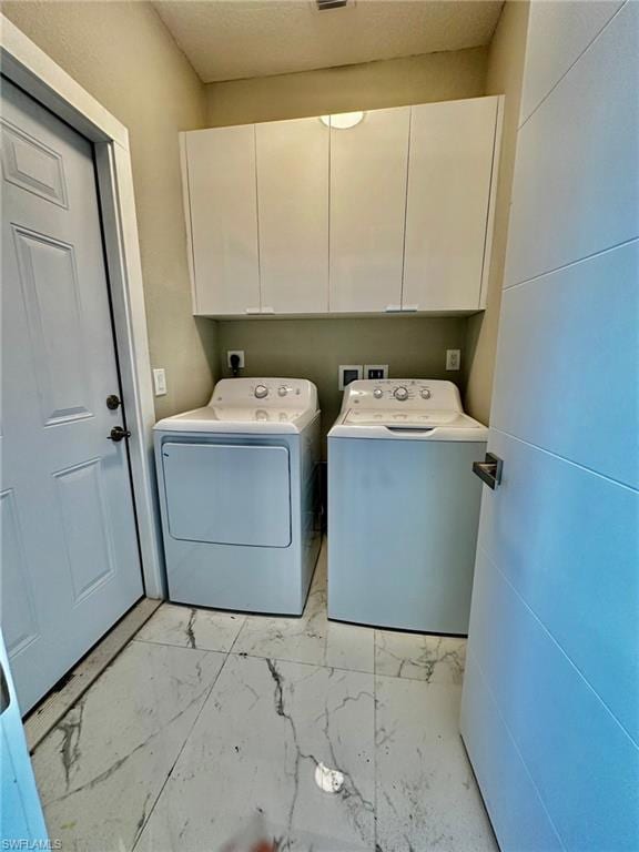 Washroom featuring cabinets and washer and clothes dryer