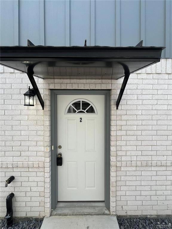 View of exterior entry with brick siding and board and batten siding