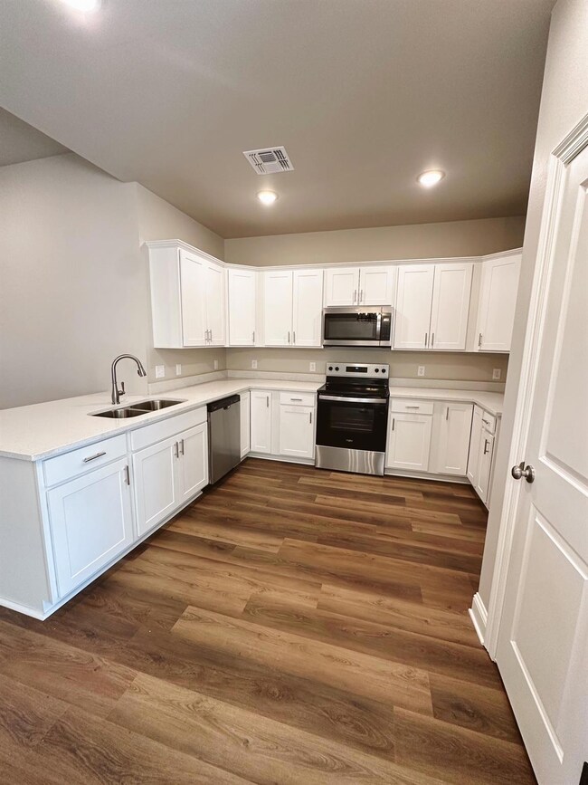 Kitchen with white cabinetry, sink, kitchen penins