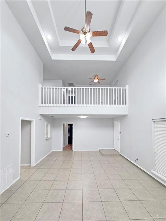 Unfurnished living room with a raised ceiling, a towering ceiling, and light tile patterned floors