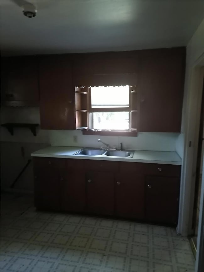 Kitchen with dark brown cabinetry, sink, and light