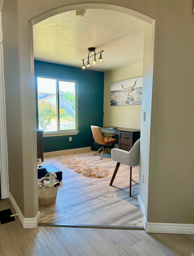 Office space with light wood-style floors, arched walkways, and a textured ceiling