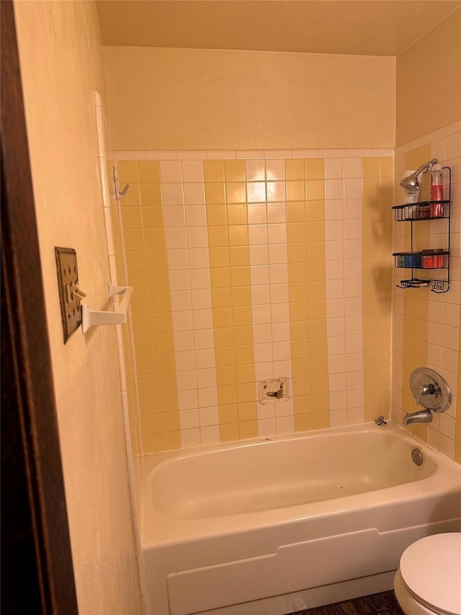 Bathroom with tiled shower / bath combo and toilet
